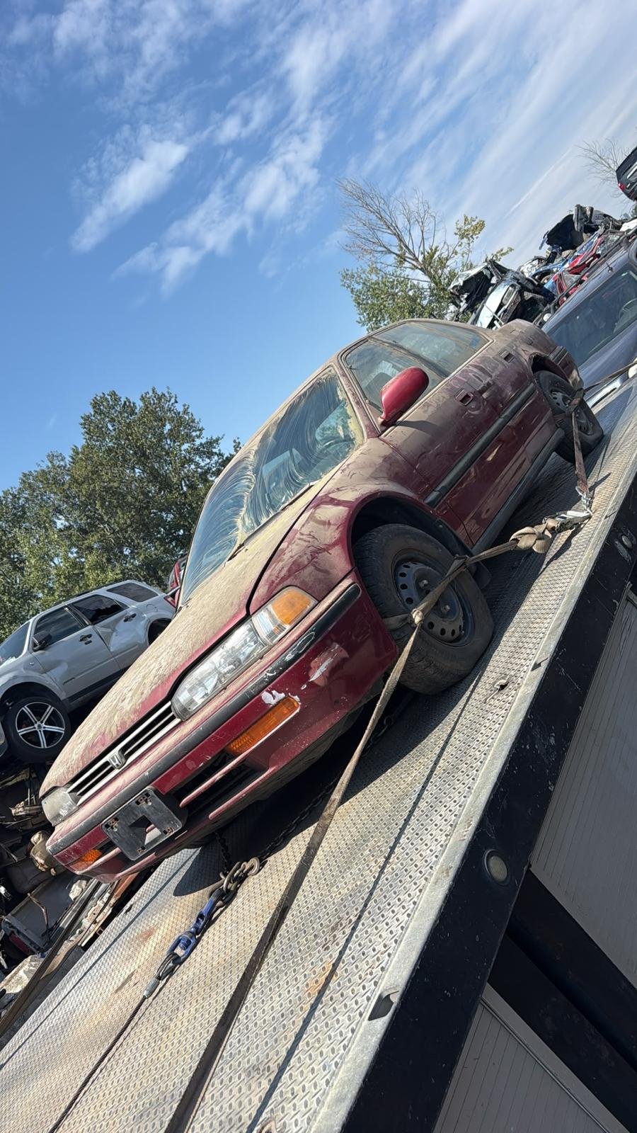 An older vehicle secured on a flatbed tow deck