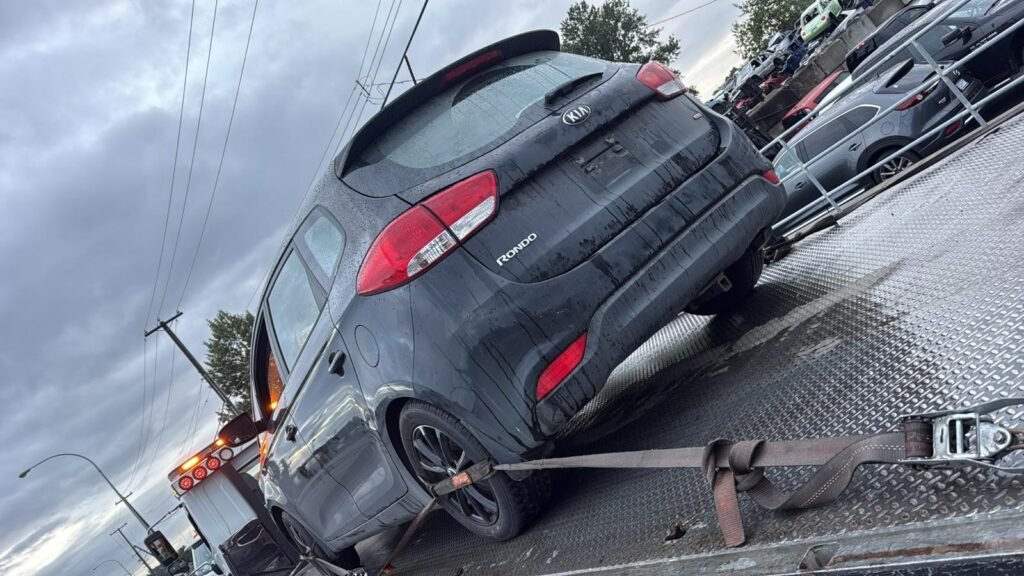 A dark SUV secured on a flatbed tow truck