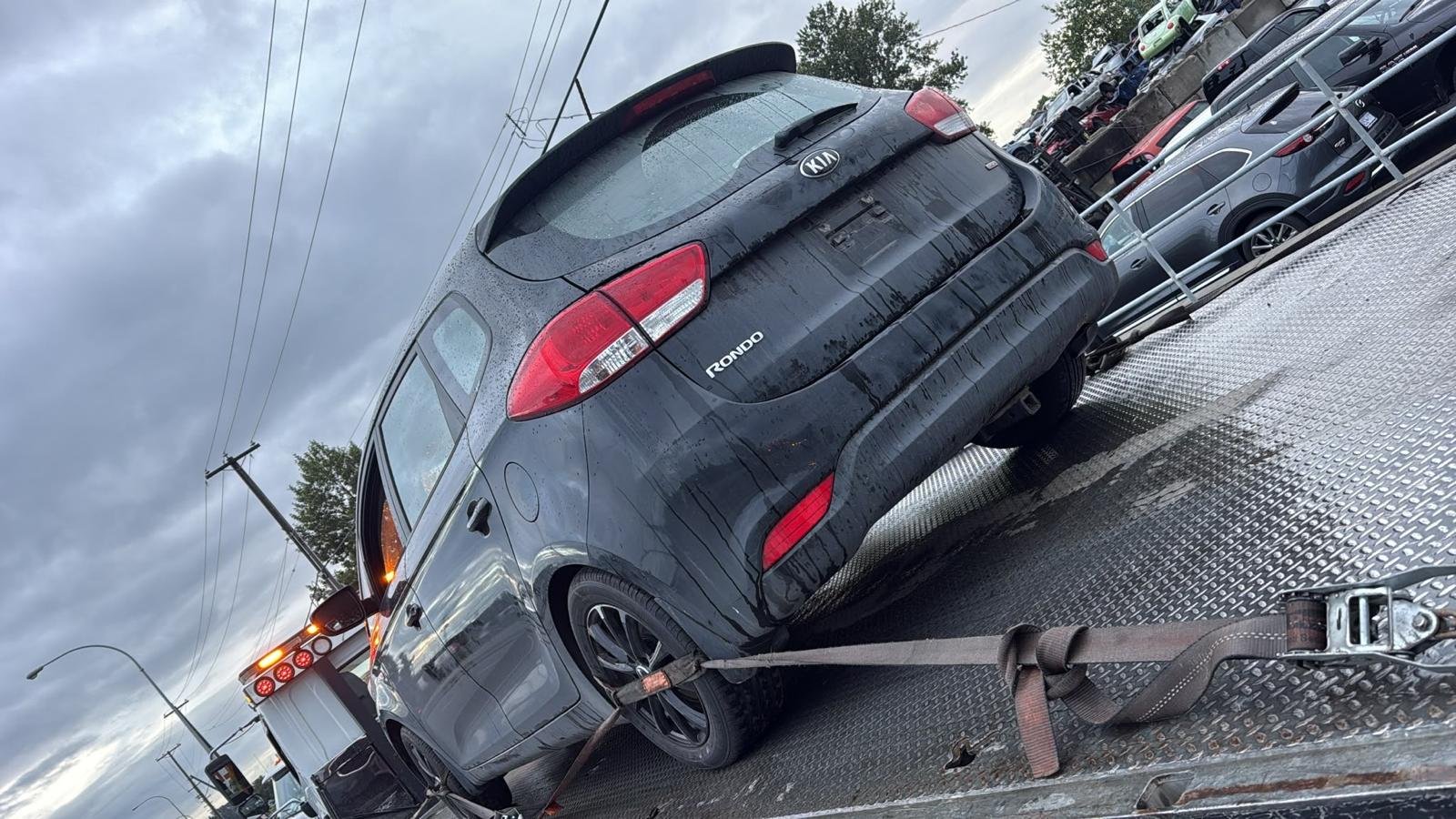 A dark SUV secured on a flatbed tow truck